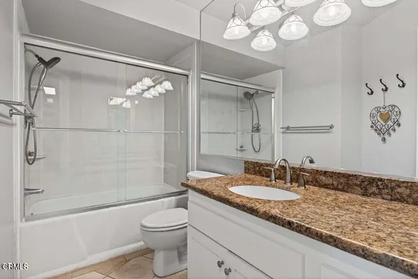 a bathroom with a granite countertop sink toilet and shower