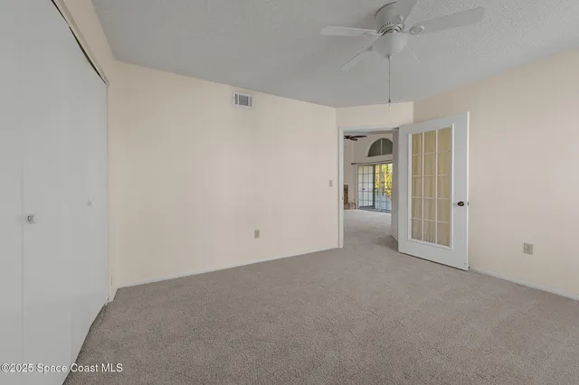 an empty room with chandelier fan and windows