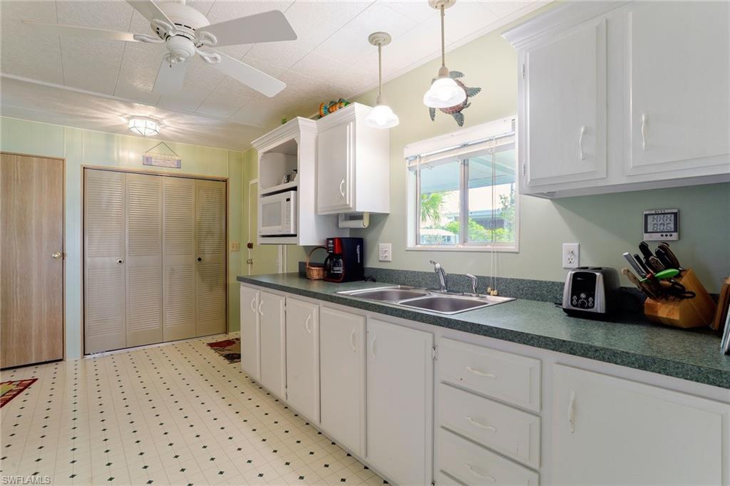 105 Audubon Road Naples, FL 34114 - Photo 5 of 30 a kitchen with granite countertop a sink a window stainless steel appliances and cabinets