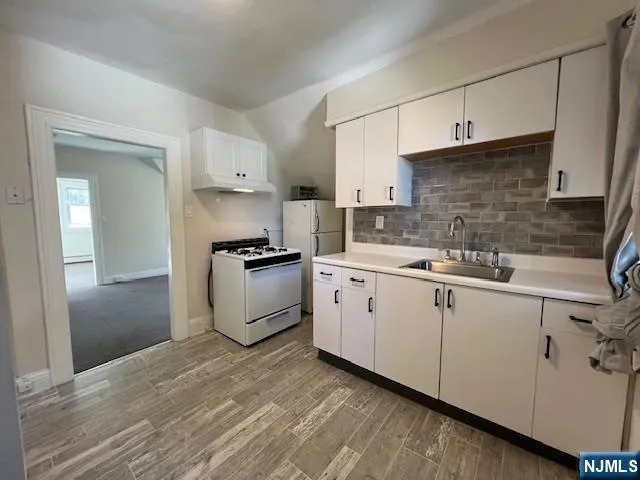 a kitchen with granite countertop white cabinets and white appliances