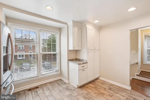 an empty room with wooden floor cabinet and windows