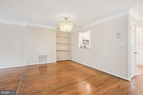 an empty room with wooden floor ceiling fan and windows