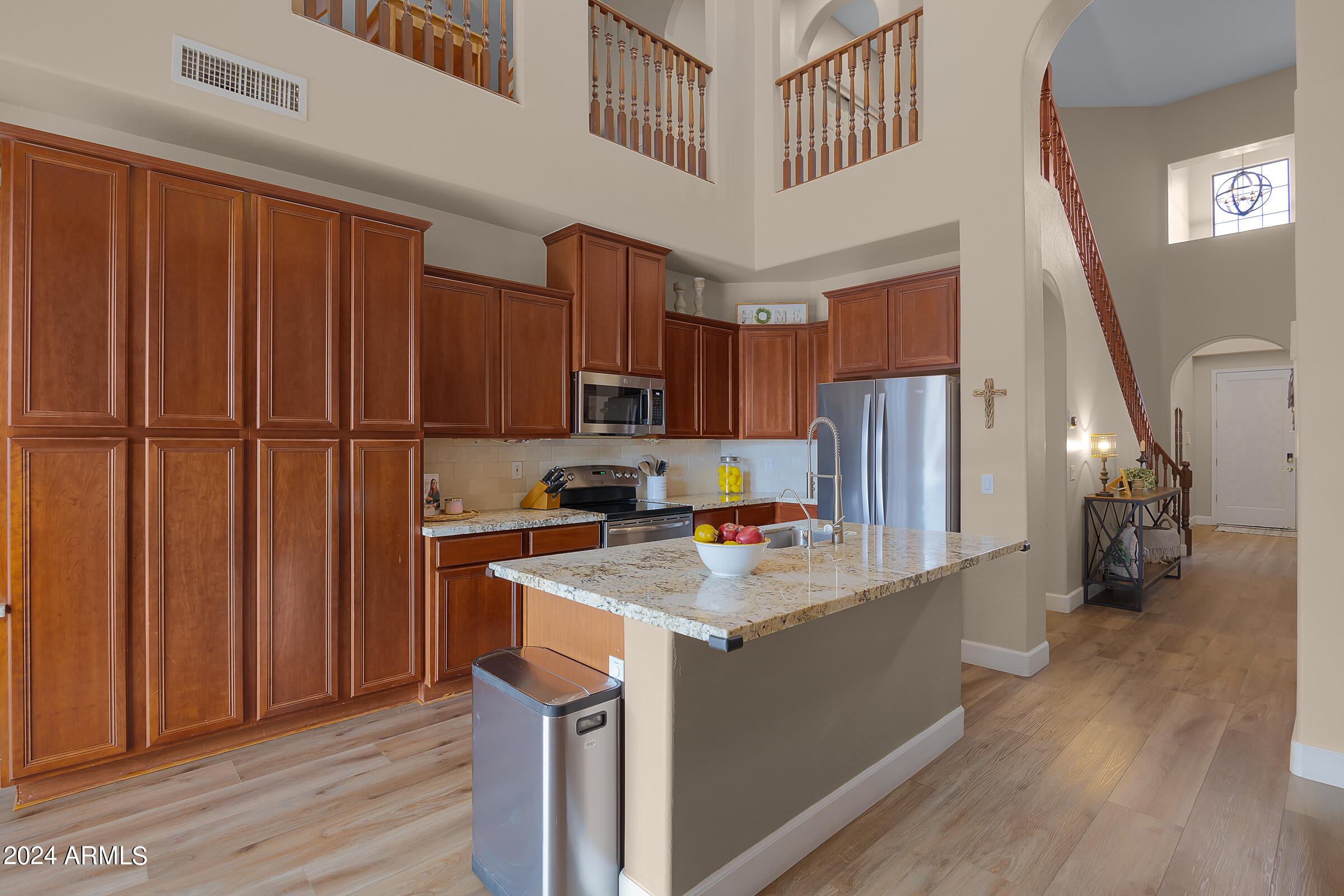 2909 West Silver Fox Way Phoenix, AZ 85045 - Photo 10 of 34 a kitchen with kitchen island a stove a refrigerator a sink dishwasher and wooden cabinets with wooden floor