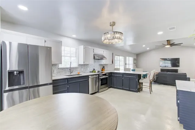 a large kitchen with kitchen island a large counter space stainless steel appliances and a dining table