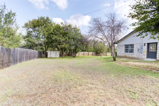 a view of a yard with a house and trees in the background