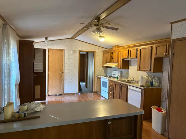 a view of living room kitchen with stainless steel appliances wooden floor and chair