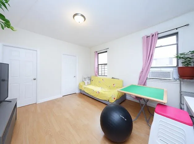 a bed sitting in a bedroom next to a window and wooden floor