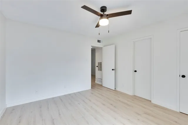 an empty room with wooden floor and ceiling fan