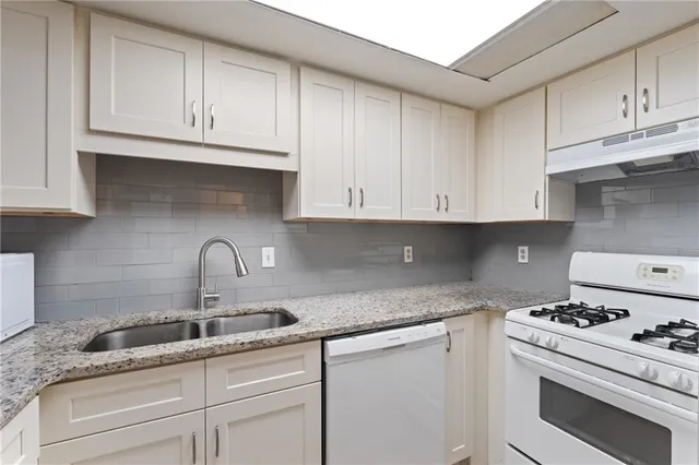 a kitchen with granite countertop white cabinets and white appliances