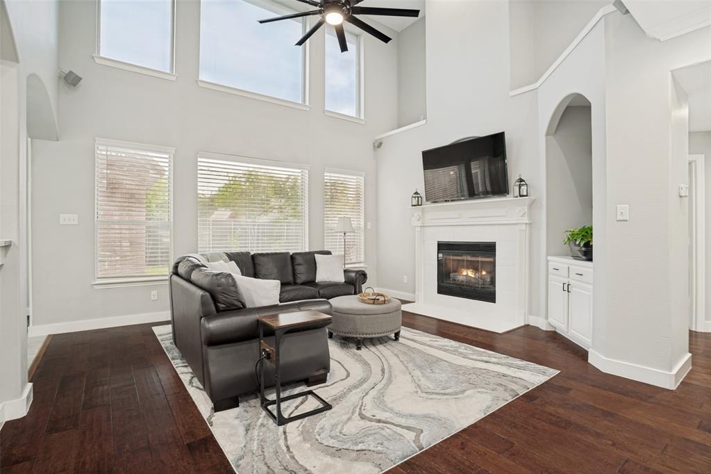 1612 Coventry Lane Allen, TX 75002 - Photo 22 of 39 Living area featuring a two-story ceiling, a ceiling fan, and wood-finish flooring