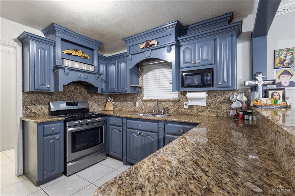 157 San Agustin Street Rio Grande City, TX 78582 - Photo 5 of 17 a kitchen with granite countertop wooden cabinets and a stove top oven