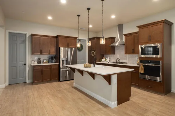 a large kitchen with stainless steel appliances kitchen island granite countertop a stove a refrigerator a oven and a sink with large countertops