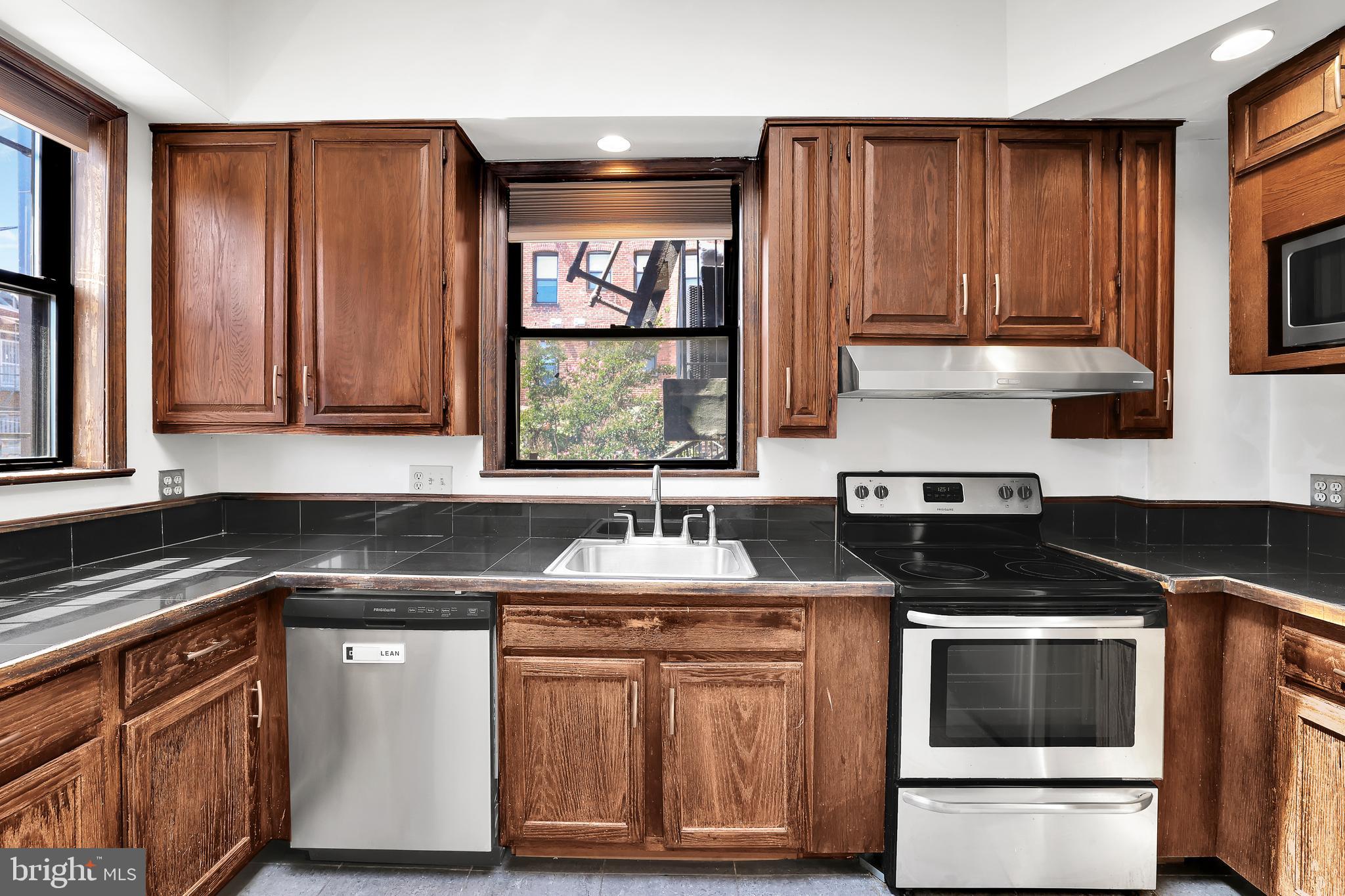 1828 California Street Northwest, Unit A Washington, DC 20009 - Photo 15 of 52 a kitchen with granite countertop a stove sink and cabinets