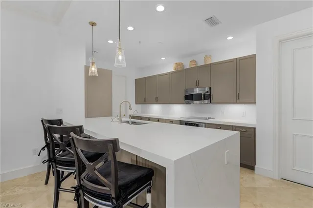 a kitchen with stainless steel appliances granite countertop a stove a refrigerator a kitchen island a table and chairs