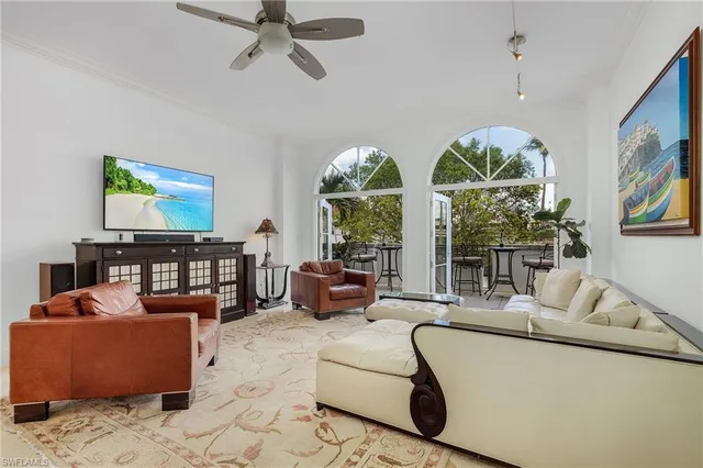 a living room with furniture a floor to ceiling window and a flat screen tv