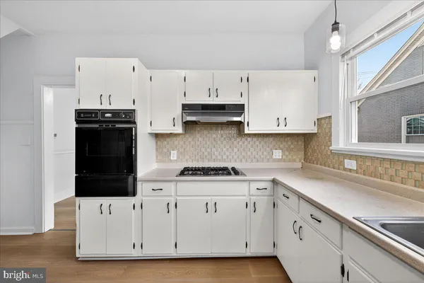 a kitchen with white cabinets and black appliances