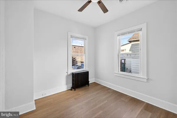 an empty room with chandelier fan and windows