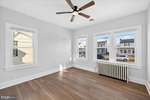 an empty room with wooden floor a ceiling fan and windows