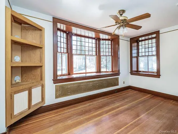 a view of an empty room with a window and wooden floor