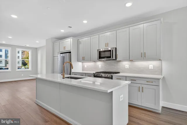 a kitchen with stainless steel appliances granite countertop a stove a sink and a refrigerator