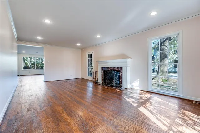 an empty room with wooden floor fireplace and windows