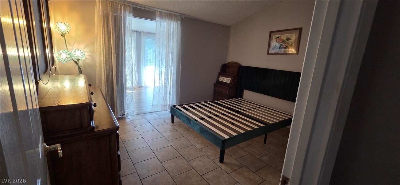 2297 East Desert Inn Road, Unit 2 Las Vegas, NV 89169 - Photo 10 of 13 Tiled flooring and sliding doors leading to an adjacent space anchor this versatile bedroom.