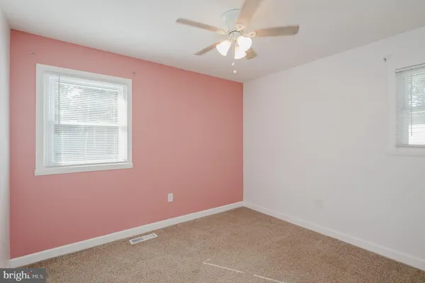 an empty room with a window and chandelier fan