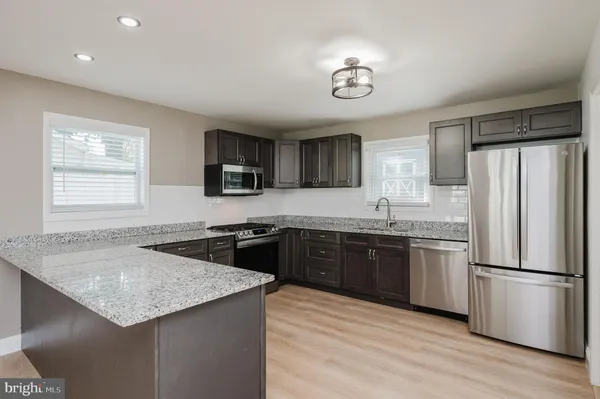 a kitchen with stainless steel appliances granite countertop a sink stove refrigerator and microwave