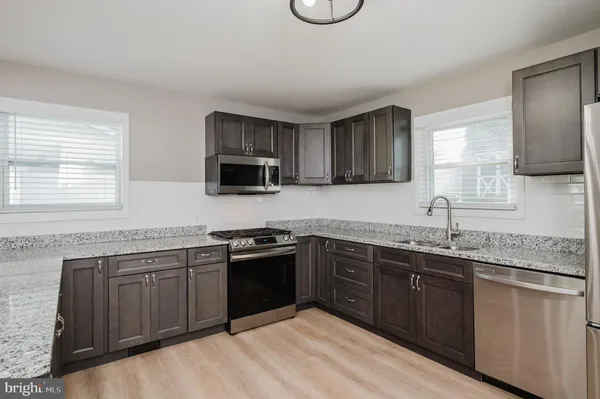 a kitchen with stainless steel appliances granite countertop a sink dishwasher stove top oven and wooden cabinets