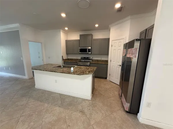 a kitchen with stainless steel appliances granite countertop a refrigerator a stove and a sink