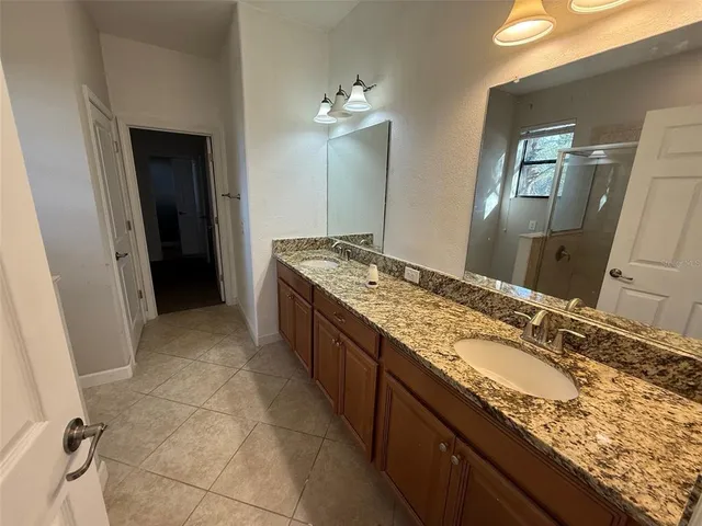 a bathroom with a granite countertop double vanity sink and mirror