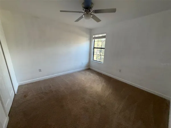 an empty room with a window and a ceiling fan