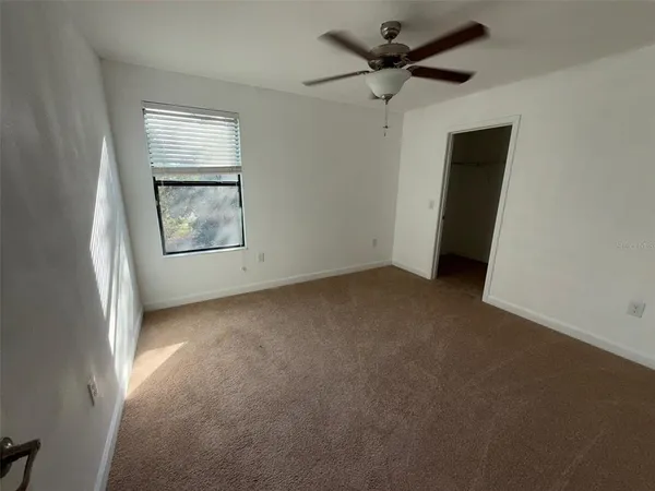 an empty room with windows and a ceiling fan