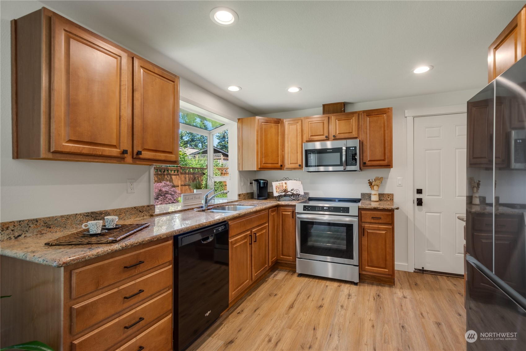 14545 166th Place Southeast Renton, WA 98059 - Photo 10 of 28 a kitchen with stainless steel appliances granite countertop wooden cabinets a sink a stove a refrigerator and island with wooden floors