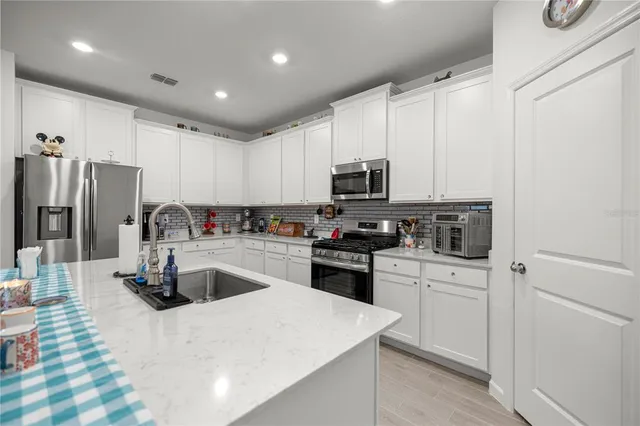 a kitchen with kitchen island a counter top space a sink stainless steel appliances and cabinets