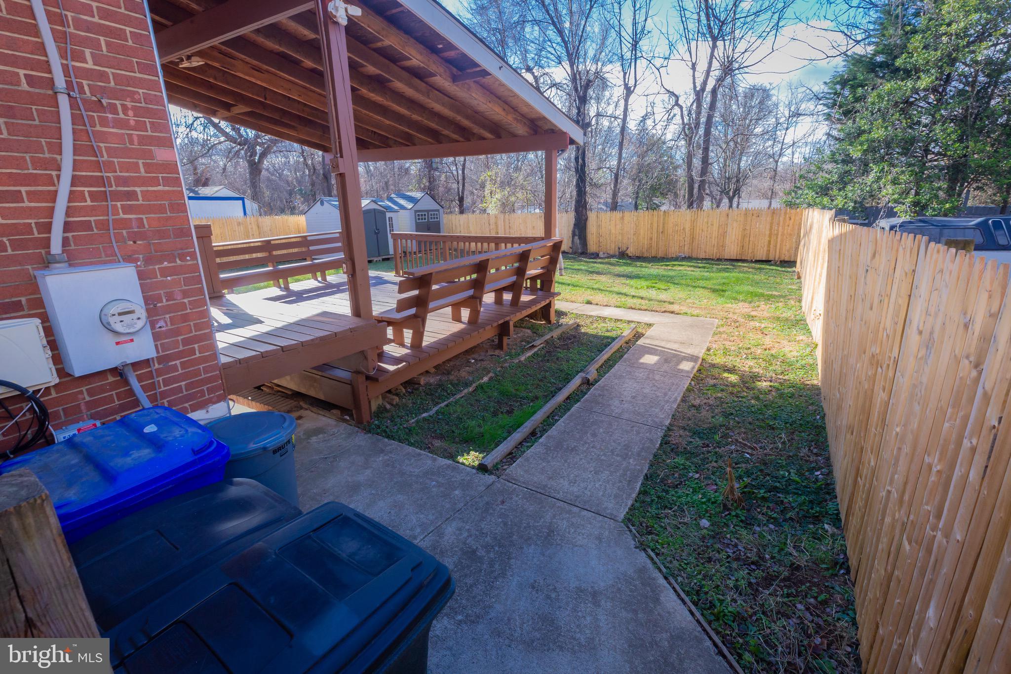 3945 Wendy Lane Silver Spring, MD 20906 - Photo 41 of 45 a view of a backyard with table and chairs under an umbrella with a barbeque grill and wooden fence