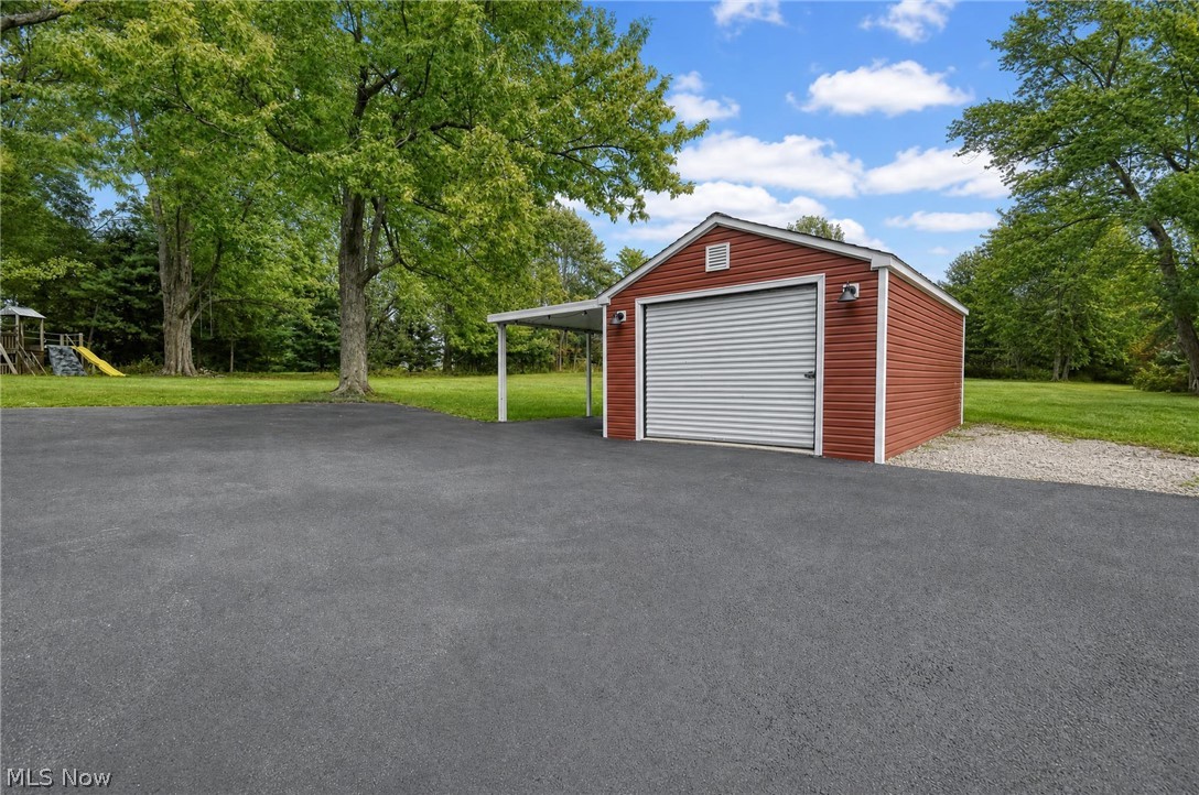 3864 State Road South Ashtabula, OH 44004 - Photo 37 of 50 Detached garage featuring red siding, a roll-up garage door, and a covered carport