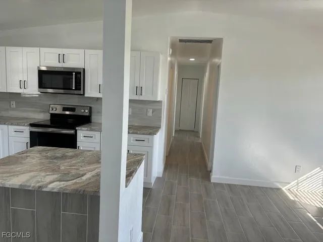 a kitchen with stainless steel appliances granite countertop a refrigerator oven a sink dishwasher and white cabinets with wooden floor