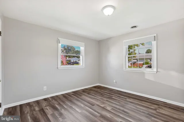 a view of an empty room with window and wooden floor