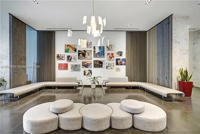 a room with lots of white furniture and a chandelier