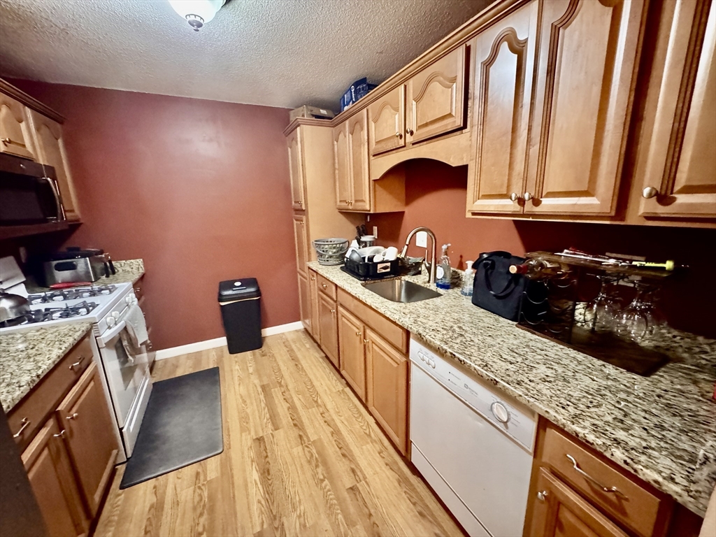 3 Greenbriar Drive, Unit 303 North Reading, MA 01864 - Photo 4 of 16 a kitchen with stainless steel appliances granite countertop a stove a sink and a microwave