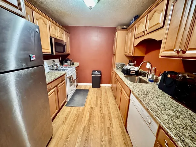 a kitchen with granite countertop a refrigerator stove and sink