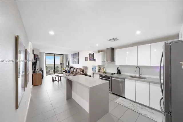 a kitchen with a sink a refrigerator and chairs
