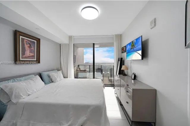 a large bedroom with a large bed and a flat tv screen on the dresser