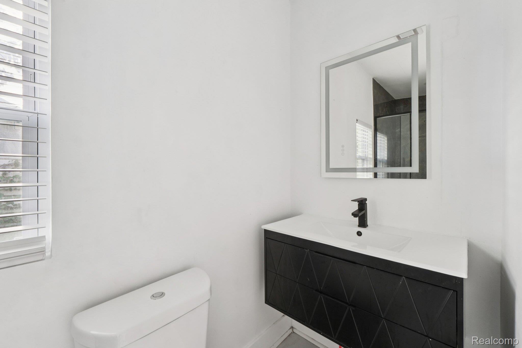 16210 Inverness Street Detroit, MI 48221 - Photo 11 of 29 Floating vanity with geometric textured finish, integrated rectangular sink, matte black faucet, and an illuminated mirror