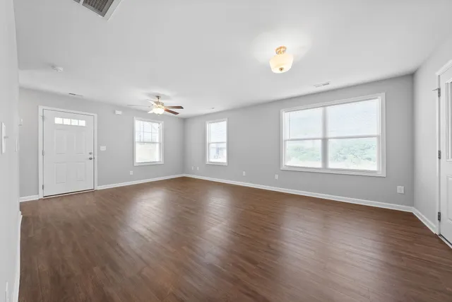 an empty room with wooden floor and windows