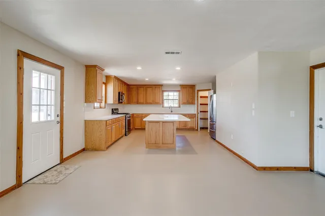 an empty room with wooden floor chandelier fan and windows