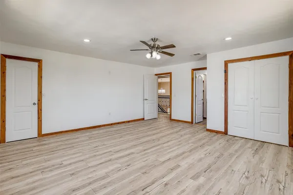 a view of empty room with wooden floor and fan