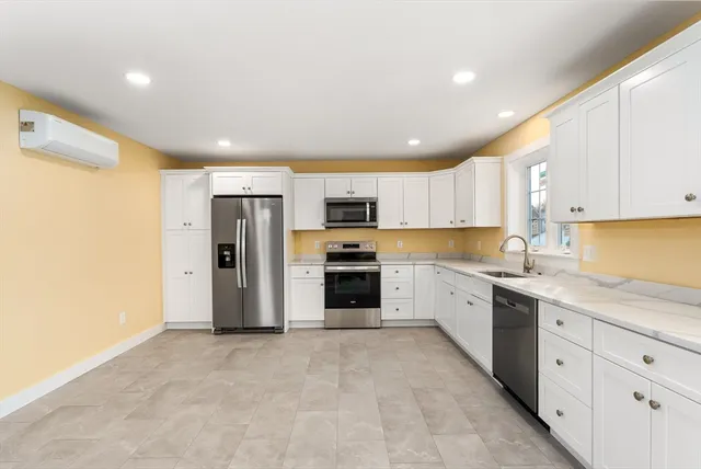 a large kitchen with stainless steel appliances granite countertop a stove a sink and a refrigerator