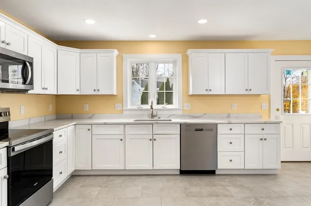 a kitchen with granite countertop white cabinets white stainless steel appliances with a sink and dishwasher
